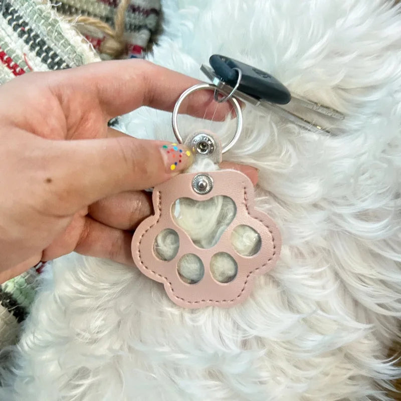 Llavero portátil multifuncional con diseño de huella de gato, fabricado en cuero, con compartimento para guardar pelo o recuerdos de mascotas.
