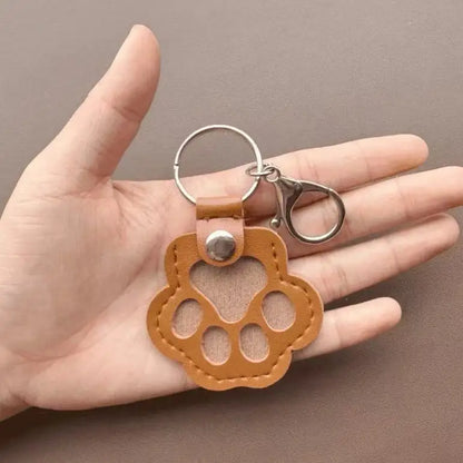 Llavero portátil multifuncional con diseño de huella de gato, fabricado en cuero, con compartimento para guardar pelo o recuerdos de mascotas.