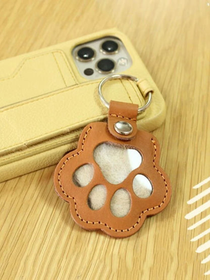 Llavero portátil multifuncional con diseño de huella de gato, fabricado en cuero, con compartimento para guardar pelo o recuerdos de mascotas.