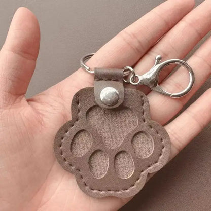 Llavero portátil multifuncional con diseño de huella de gato, fabricado en cuero, con compartimento para guardar pelo o recuerdos de mascotas.