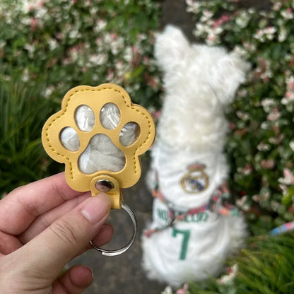 Llavero portátil multifuncional con diseño de huella de gato, fabricado en cuero, con compartimento para guardar pelo o recuerdos de mascotas.