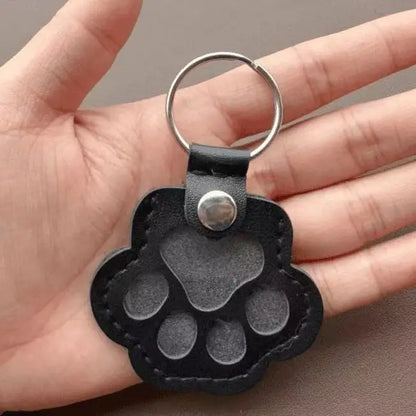 Llavero portátil multifuncional con diseño de huella de gato, fabricado en cuero, con compartimento para guardar pelo o recuerdos de mascotas.