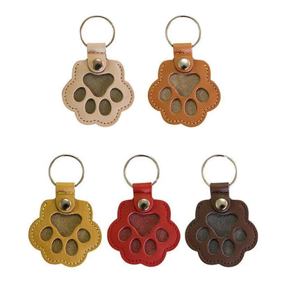 Llavero portátil multifuncional con diseño de huella de gato, fabricado en cuero, con compartimento para guardar pelo o recuerdos de mascotas.