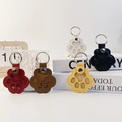 Llavero portátil multifuncional con diseño de huella de gato, fabricado en cuero, con compartimento para guardar pelo o recuerdos de mascotas.