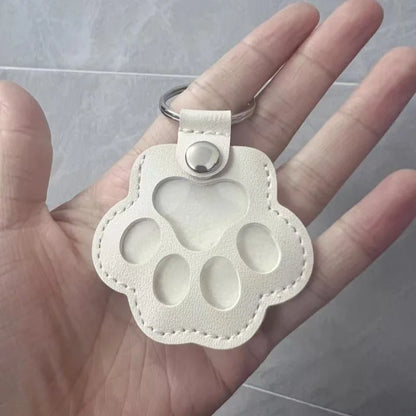Llavero portátil multifuncional con diseño de huella de gato, fabricado en cuero, con compartimento para guardar pelo o recuerdos de mascotas.