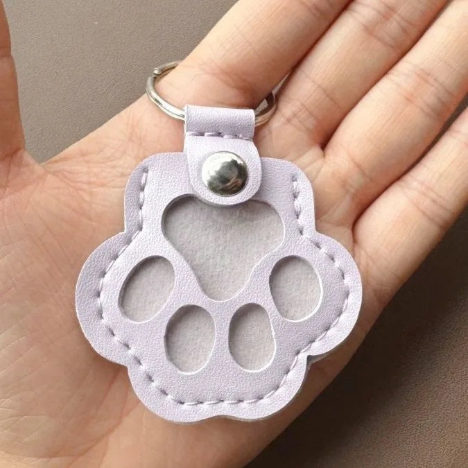 Llavero portátil multifuncional con diseño de huella de gato, fabricado en cuero, con compartimento para guardar pelo o recuerdos de mascotas.