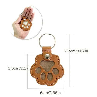 Llavero portátil multifuncional con diseño de huella de gato, fabricado en cuero, con compartimento para guardar pelo o recuerdos de mascotas.