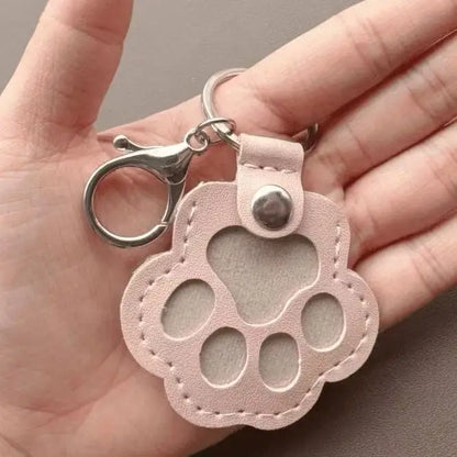 Llavero portátil multifuncional con diseño de huella de gato, fabricado en cuero, con compartimento para guardar pelo o recuerdos de mascotas.
