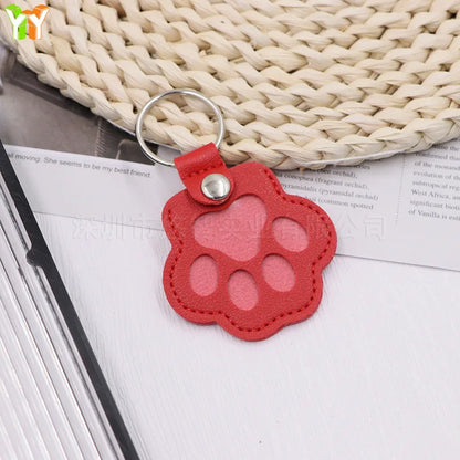 Llavero portátil multifuncional con diseño de huella de gato, fabricado en cuero, con compartimento para guardar pelo o recuerdos de mascotas.