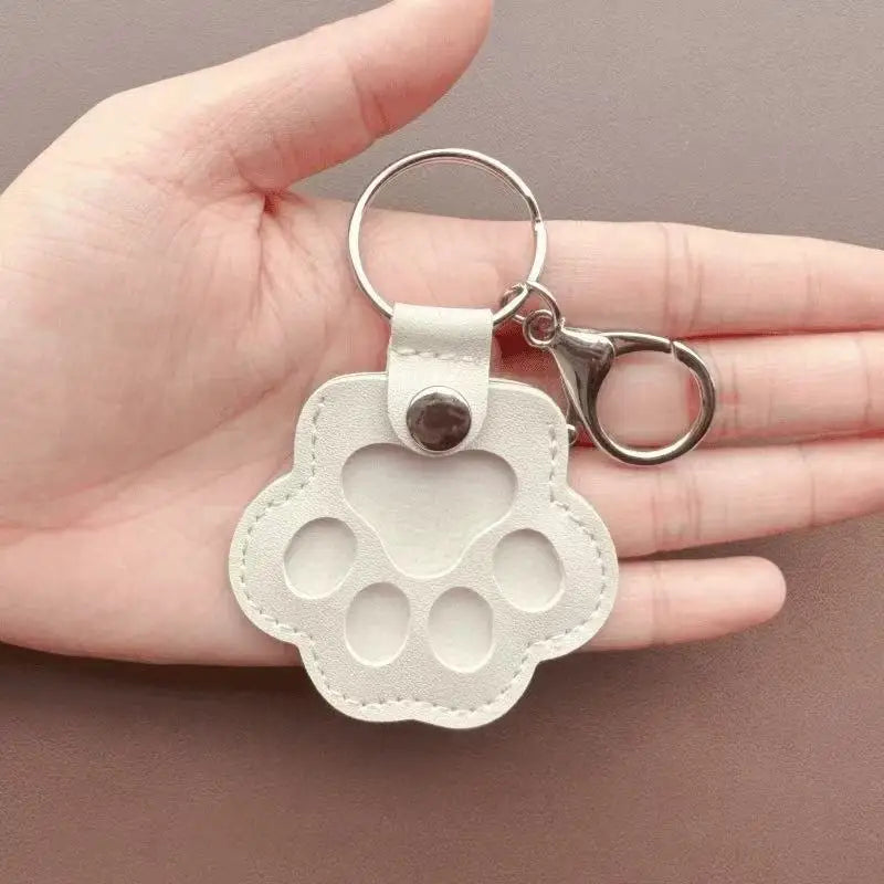 Llavero portátil multifuncional con diseño de huella de gato, fabricado en cuero, con compartimento para guardar pelo o recuerdos de mascotas.